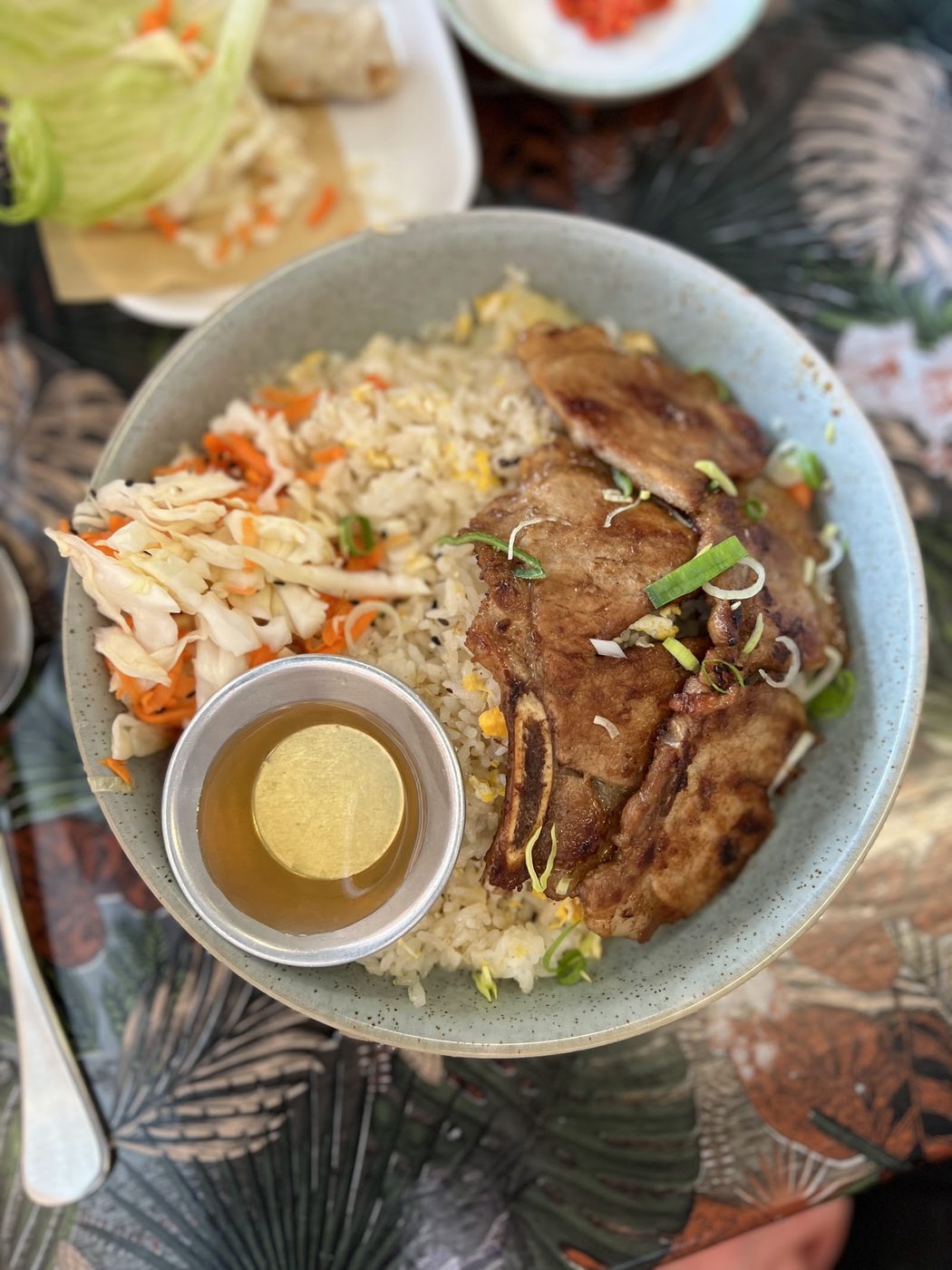 A grilled chop, bone in, over fried rice with pickled carrot and cabbage